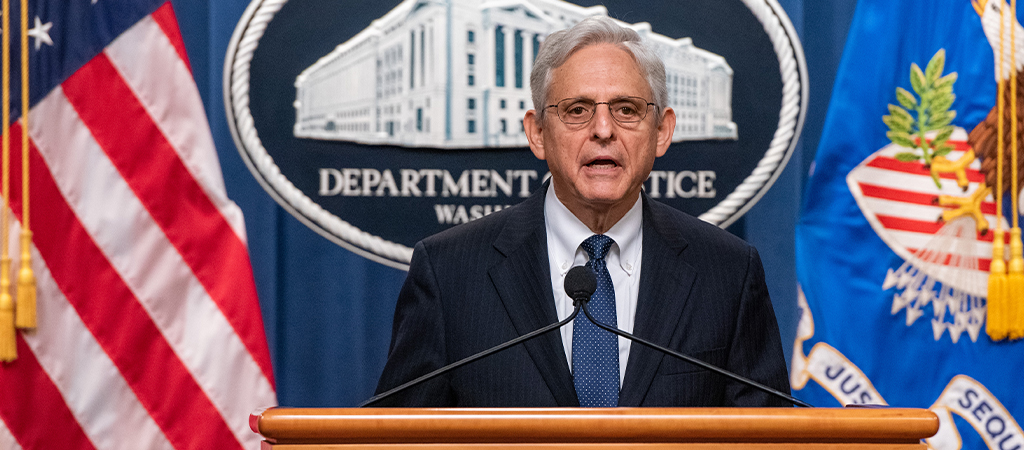 AG Merrick Garland at podium with flags and DOJ logo in background